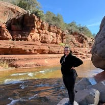 Jennifer beside the water and red rocks at Slide Rock State Park, Arizona